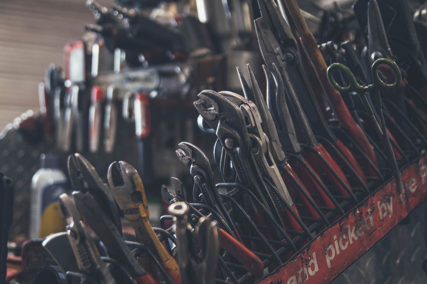 Assorted hand tools and hardware laid out on a wooden work surface